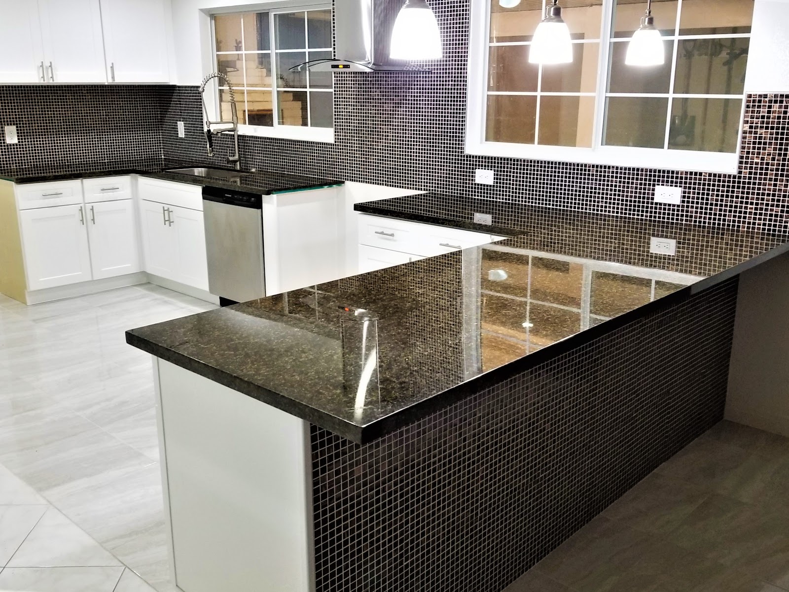 Remodeled kitchen with white cabinets, dark granite counters and mosaic backsplash