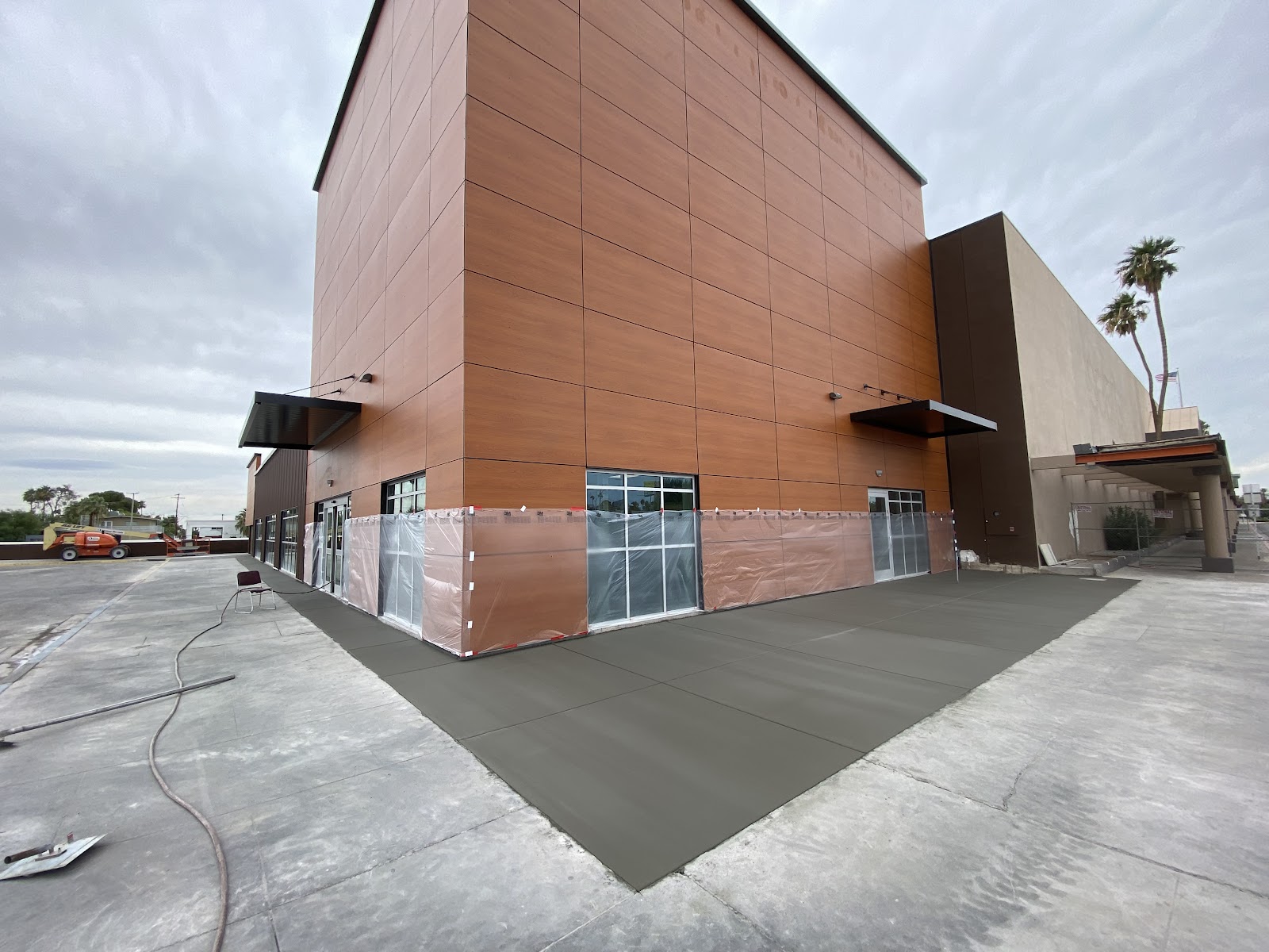 Freshly poured concrete apron around commercial building with wood-panel facade