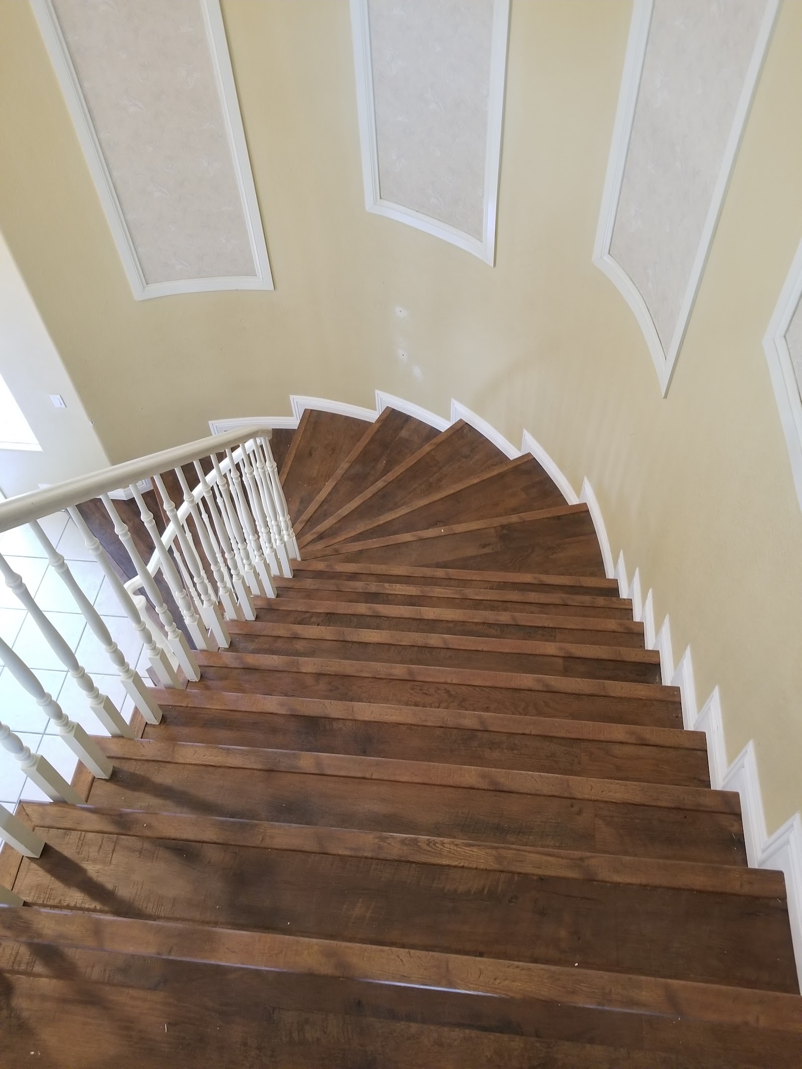 Curved hardwood staircase viewed from above with white balusters